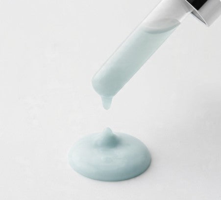 Copper peptide serum being poured from a white container on a light gray background