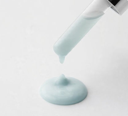 Copper peptide serum being poured from a white container on a light gray background