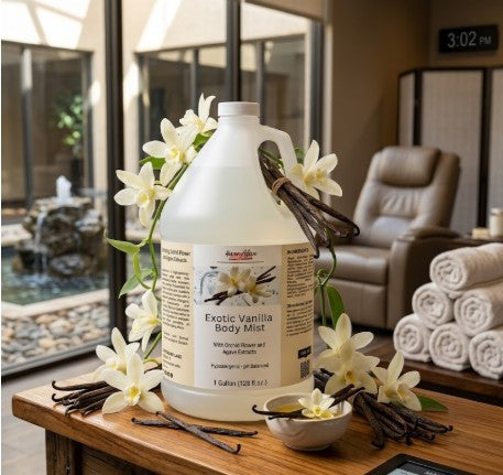 Gallon container of Exotic Vanilla Body Mist on a wooden table with vanilla beans and flowers, in a spa-like setting.