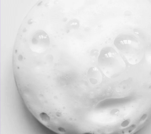 Close-up of a white creamy substance with bubbles on a light gray background