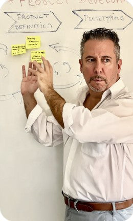 Javier Guandalini CEO at 4everalive Labs standing in front of a whiteboard with project development stages and sticky notes.