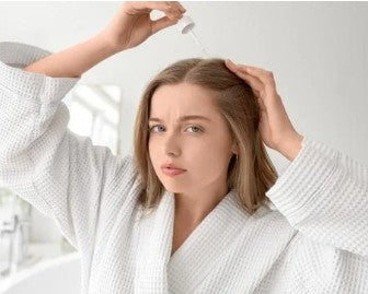 Woman in a white bathrobe applying scal pserum 