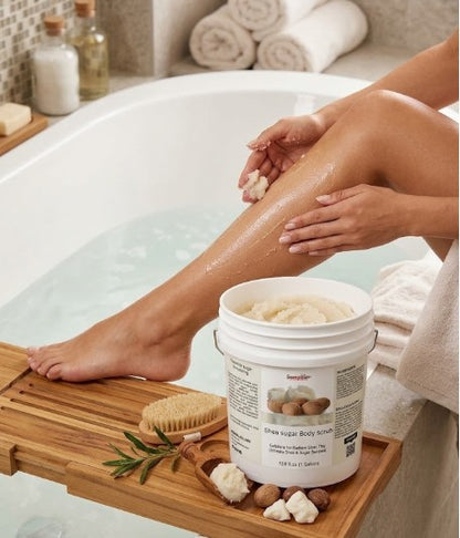Person applying body scrub to legs with a tub and bath accessories in the background